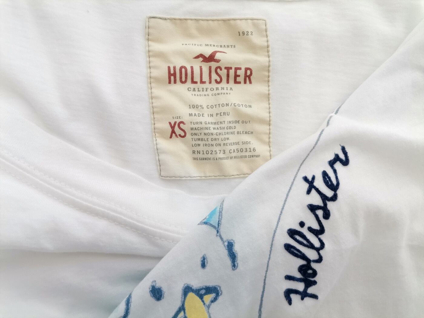 IMG_20220407_123821.jpg Hollister Rozmiar XS Kolor Biały Okrągły dekolt T-Shirt Krótki rękaw Materiał Bawełna 100%
